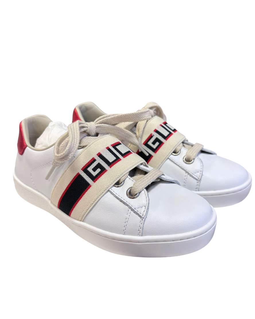 White sneakers with a Gucci logo band on a white background