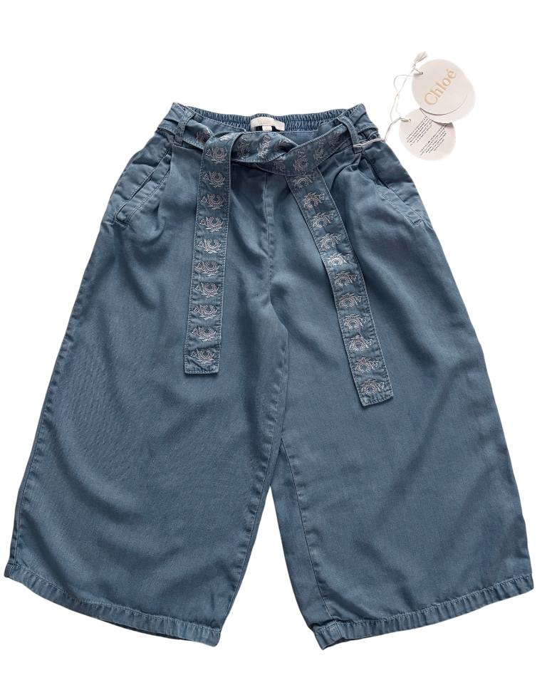 Wide leg light denim trousers on a white background