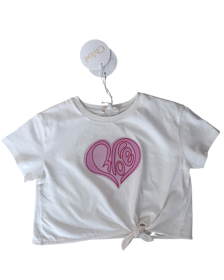 White t-shirt with pink heart design and tie front, on a white background